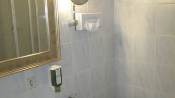 A bathroom with a sink, mirror, towel rack, and a small shelf with toiletries.