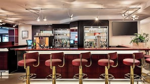 A bar area with multiple red bar stools and a bar counter.