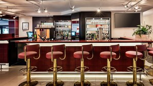 A bar area with red bar stools, a minibar, and a bar counter. - Best Western Plus Residenzhotel Lueneburg (Lueneburg)