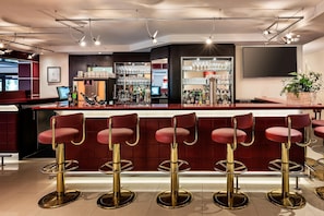 A bar area with red bar stools, a minibar, and a bar counter. - Best Western Plus Residenzhotel Lueneburg (Lueneburg)