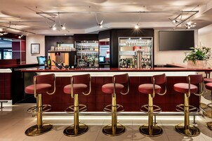 Zona de bar con taburetes rojos, un mini bar y una barra.