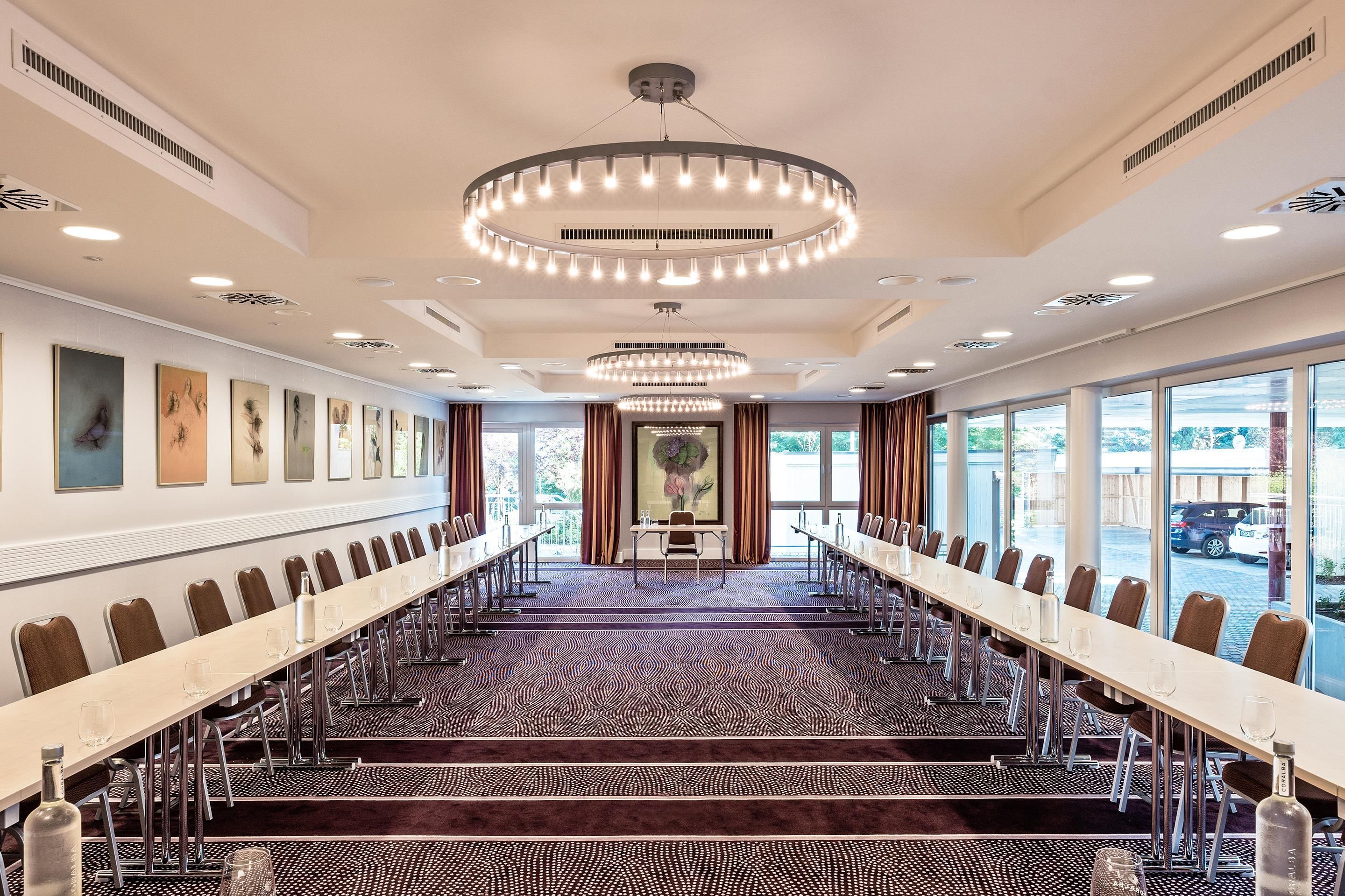 A conference room with a long table, chairs, and a patterned carpet.