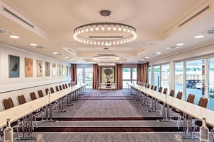 A conference room with a long table, chairs, and a patterned carpet.