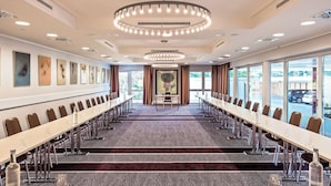 A conference room with a long table, chairs, and a patterned carpet.