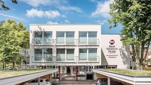 A modern Best Western PLUS hotel with a flat roof, large windows, and a covered parking area.