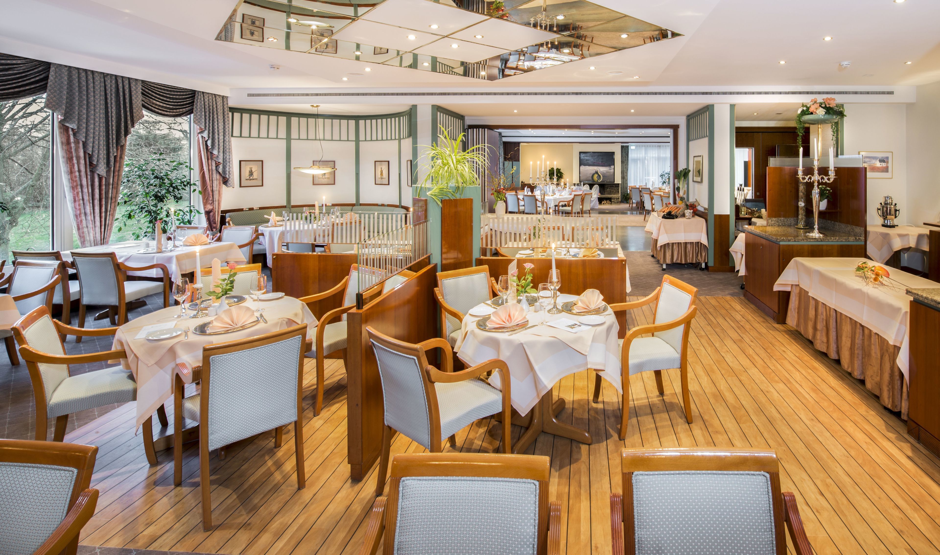A restaurant with multiple dining areas, wooden flooring, and a view of the outdoors.