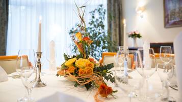 A dining table set with candles, glasses, and a floral centerpiece.