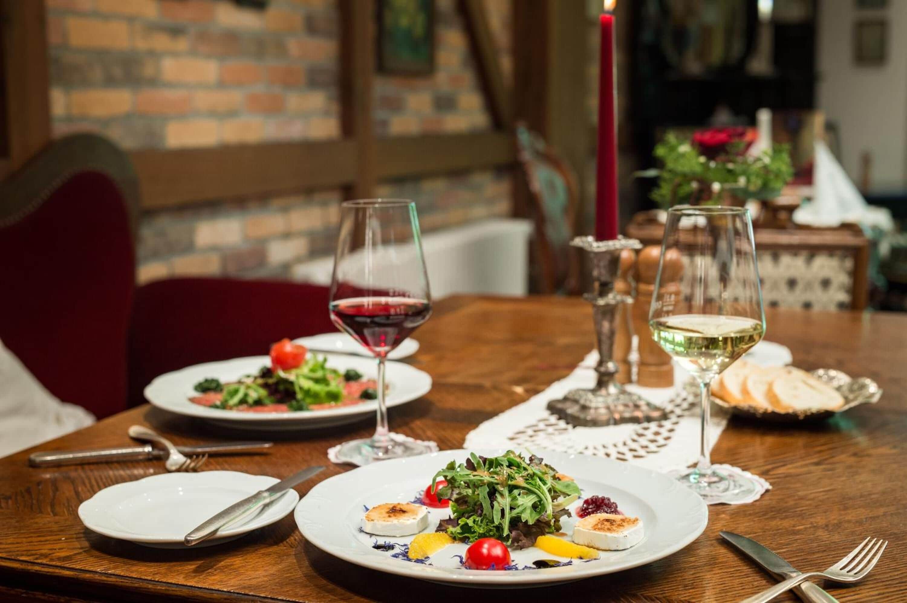 A dining table set with plates of food, glasses of wine, and cutlery.