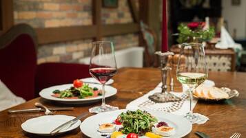 A dining table set with plates of food, glasses of wine, and cutlery.