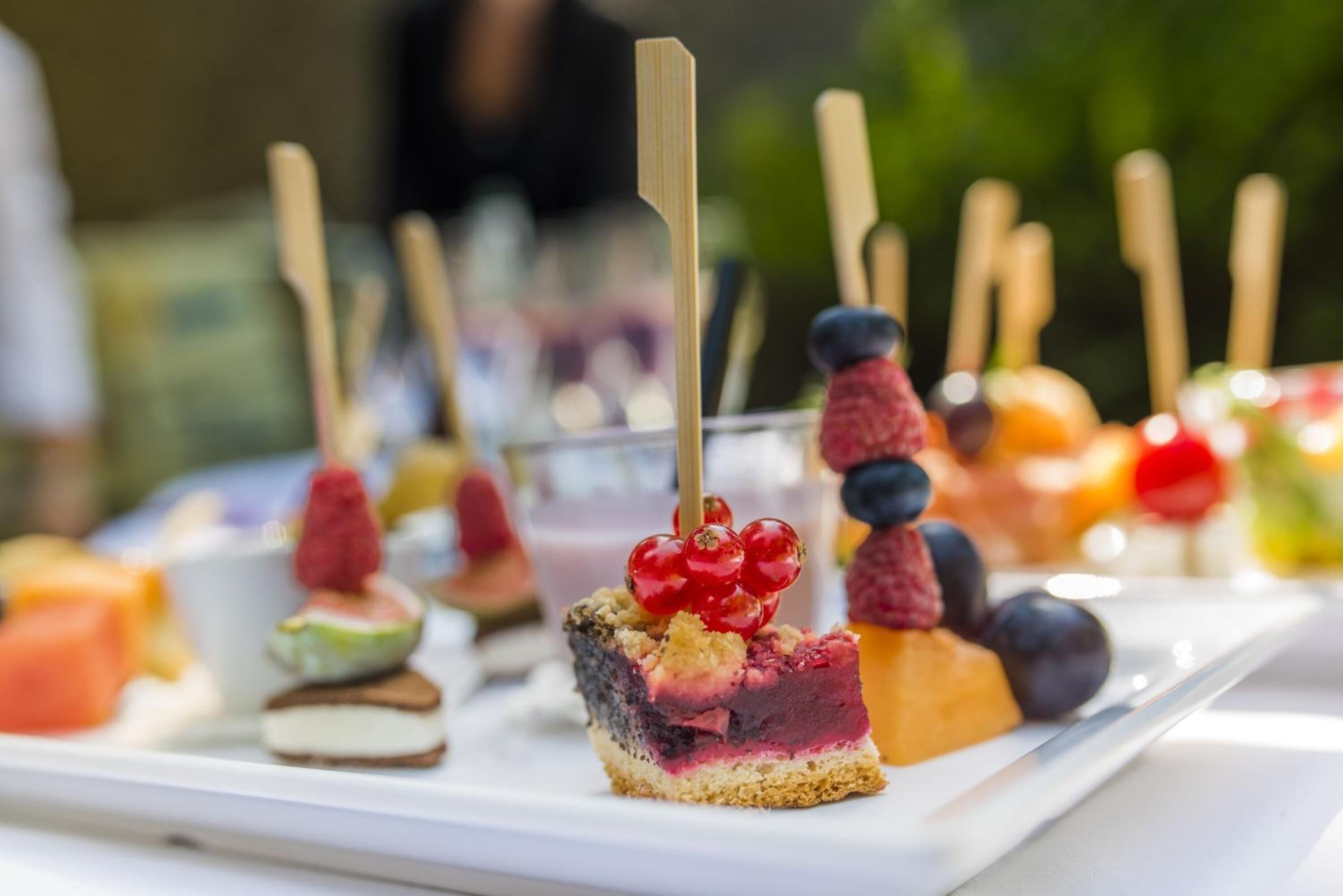 Una variedad de postres en un plato blanco, incluyendo una porción con bayas y una taza pequeña.