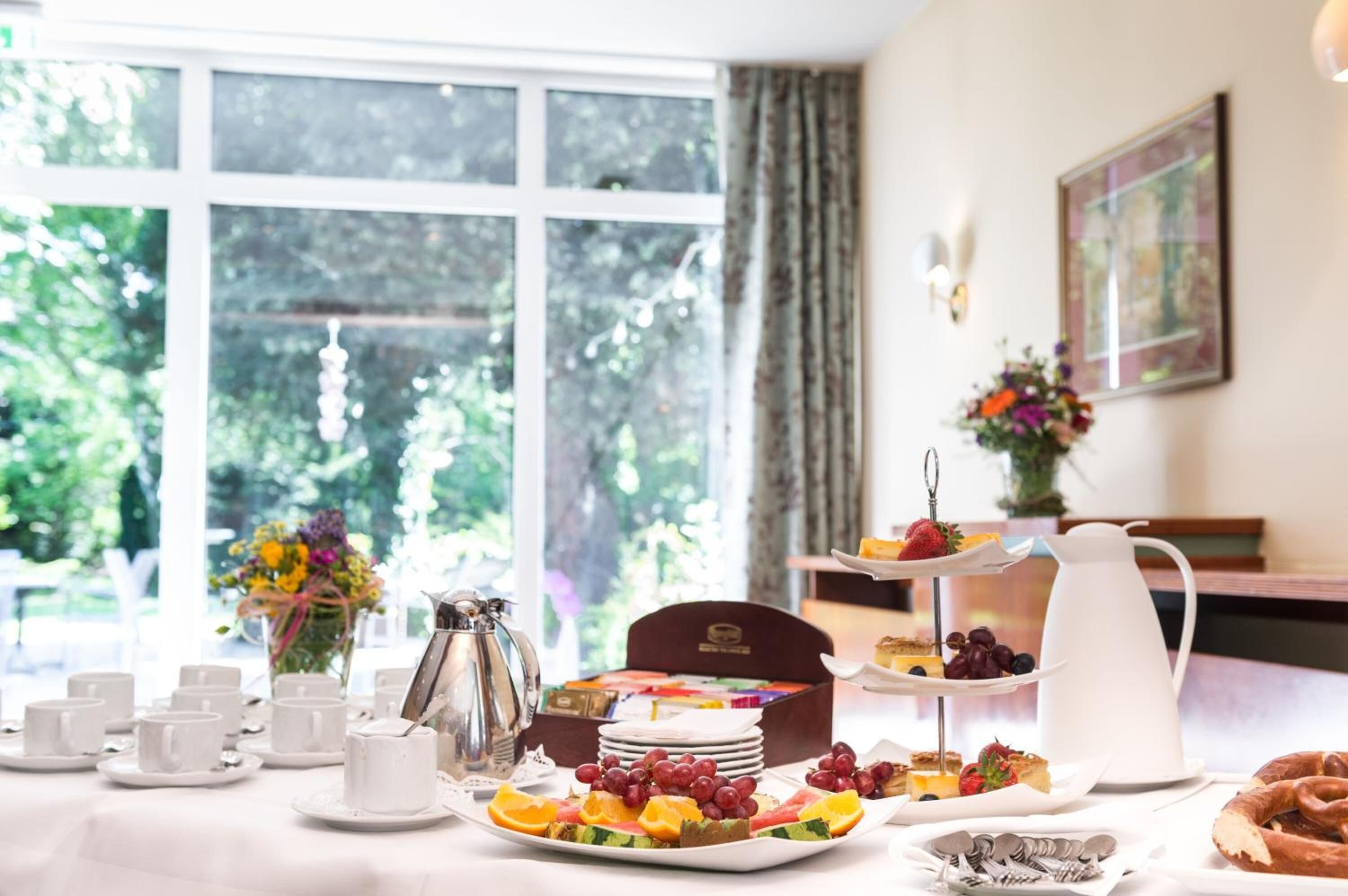 A breakfast setup with a variety of pastries, fruits, and a coffee pot on a table.