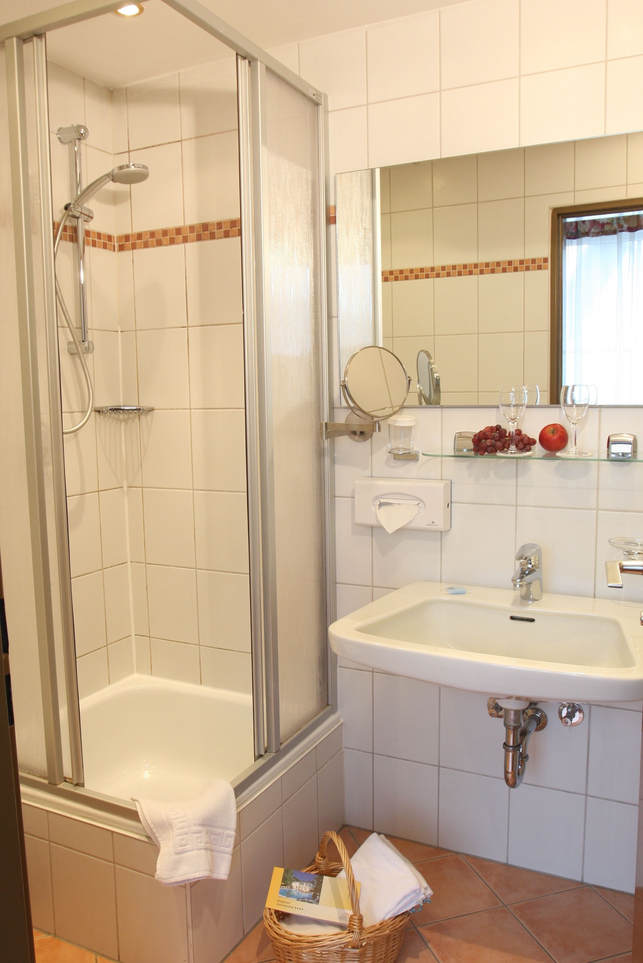A bathroom with a glass-enclosed shower, a white sink, and a mirror above it.
