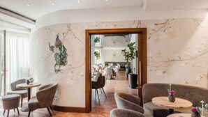 A modern interior with marble walls, a peacock mural, and a dining area with tables and chairs.