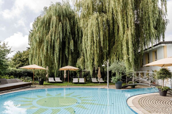 Una piscina techada, una piscina al aire libre de temporada, sombrillas