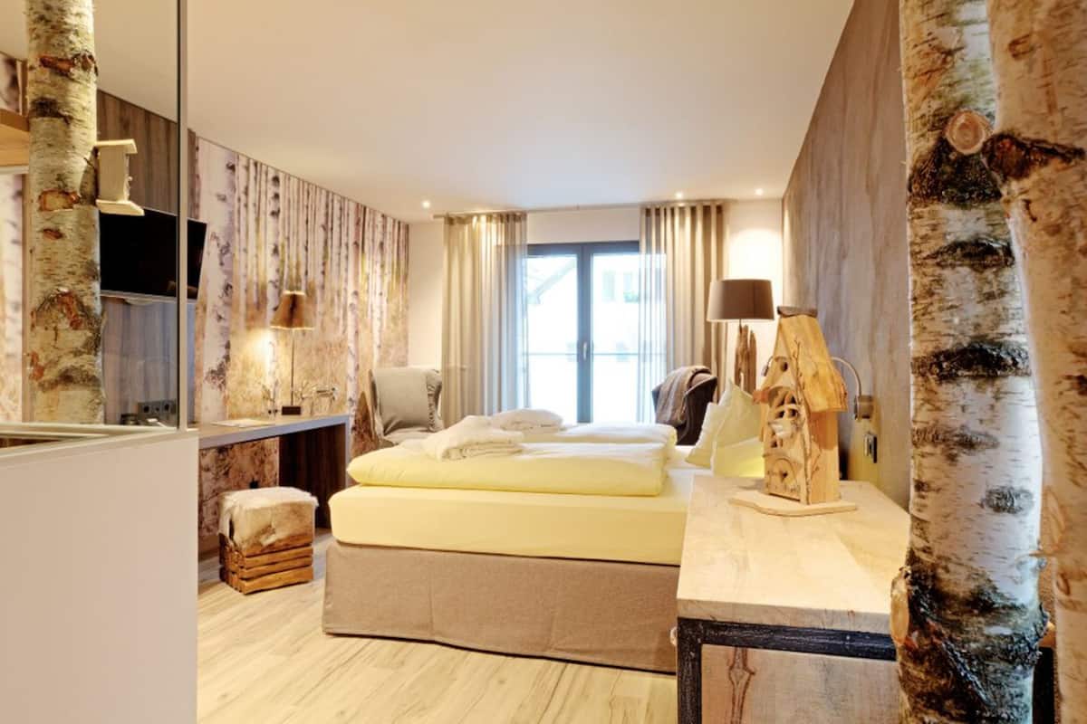 Una habitación de hotel con una cama, un escritorio, un espejo y una ventana con cortinas.