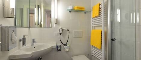 Un baño moderno con lavamanos, inodoro y cabina de ducha de vidrio.