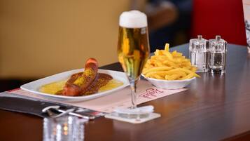 A dining table with a plate of food, a glass of beer, and salt and pepper shakers.