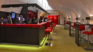 A modern bar area with a red counter, stools, and a barista station. - Hotel Ratskeller (Salzgitter)
