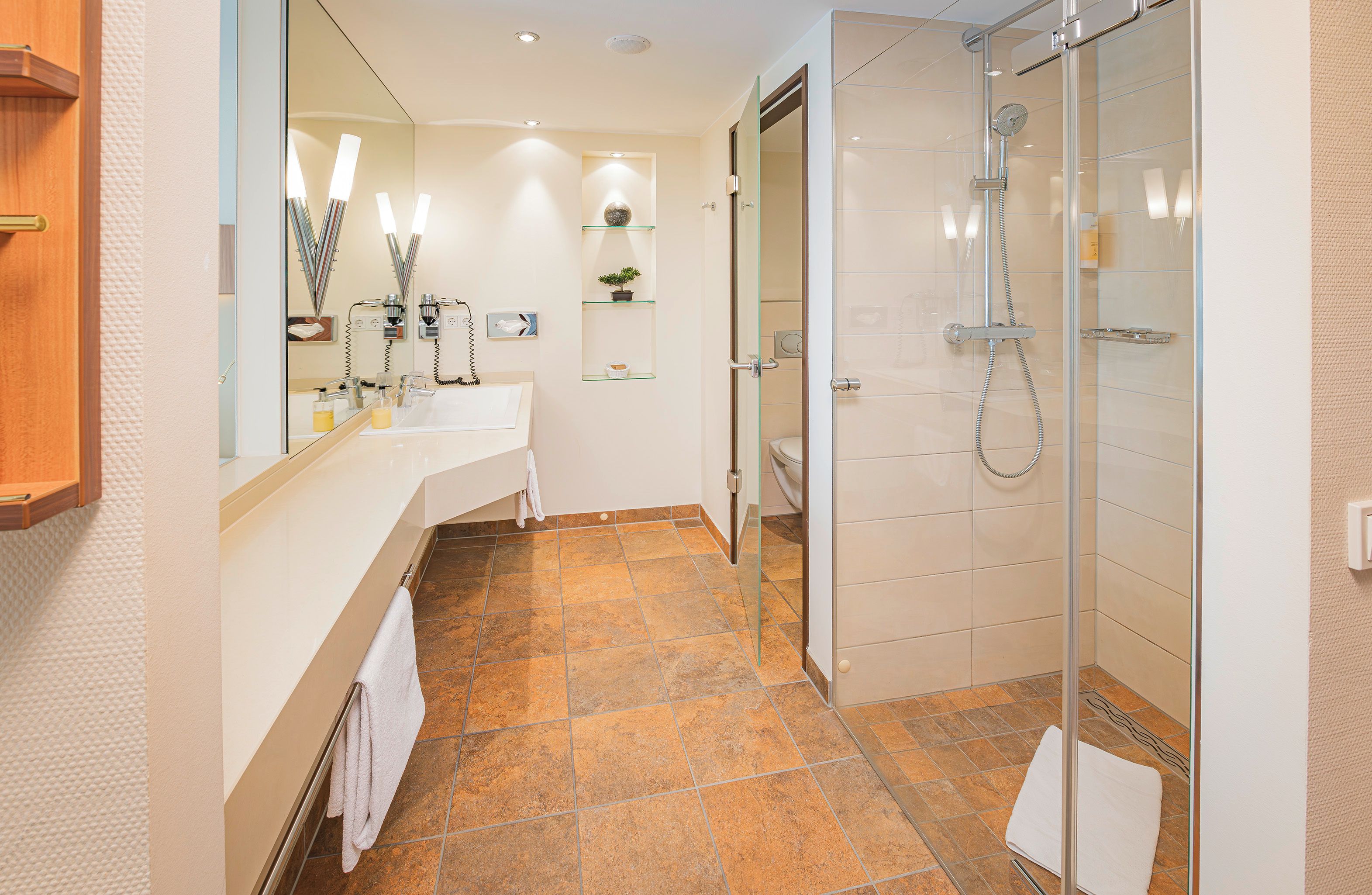 A modern bathroom with a glass shower enclosure, a large mirror, and a vanity with a sink.