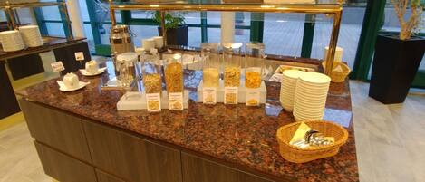 Mostrador de buffet con diversos alimentos y utensilios para servir.