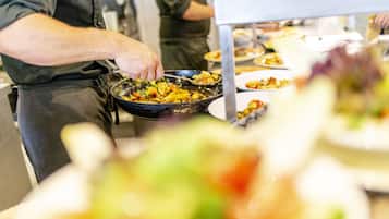 Ein reichhaltiges Buffet mit verschiedenen Speisen und einer Person, die das Essen serviert.