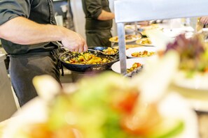 Ein reichhaltiges Buffet mit verschiedenen Speisen und einer Person, die das Essen serviert.