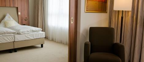 Habitación de hotel con cama, una silla, una lámpara y un cuadro en la pared.
