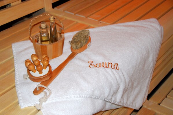 A wooden bench with a white towel and a wooden brush with a bottle of oil. - Katharinenhof Hotelgesellschaft mbH & Co. KG (Unna)