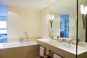 Un baño moderno con una bañera grande, dos lavamanos y un espejo amplio.
