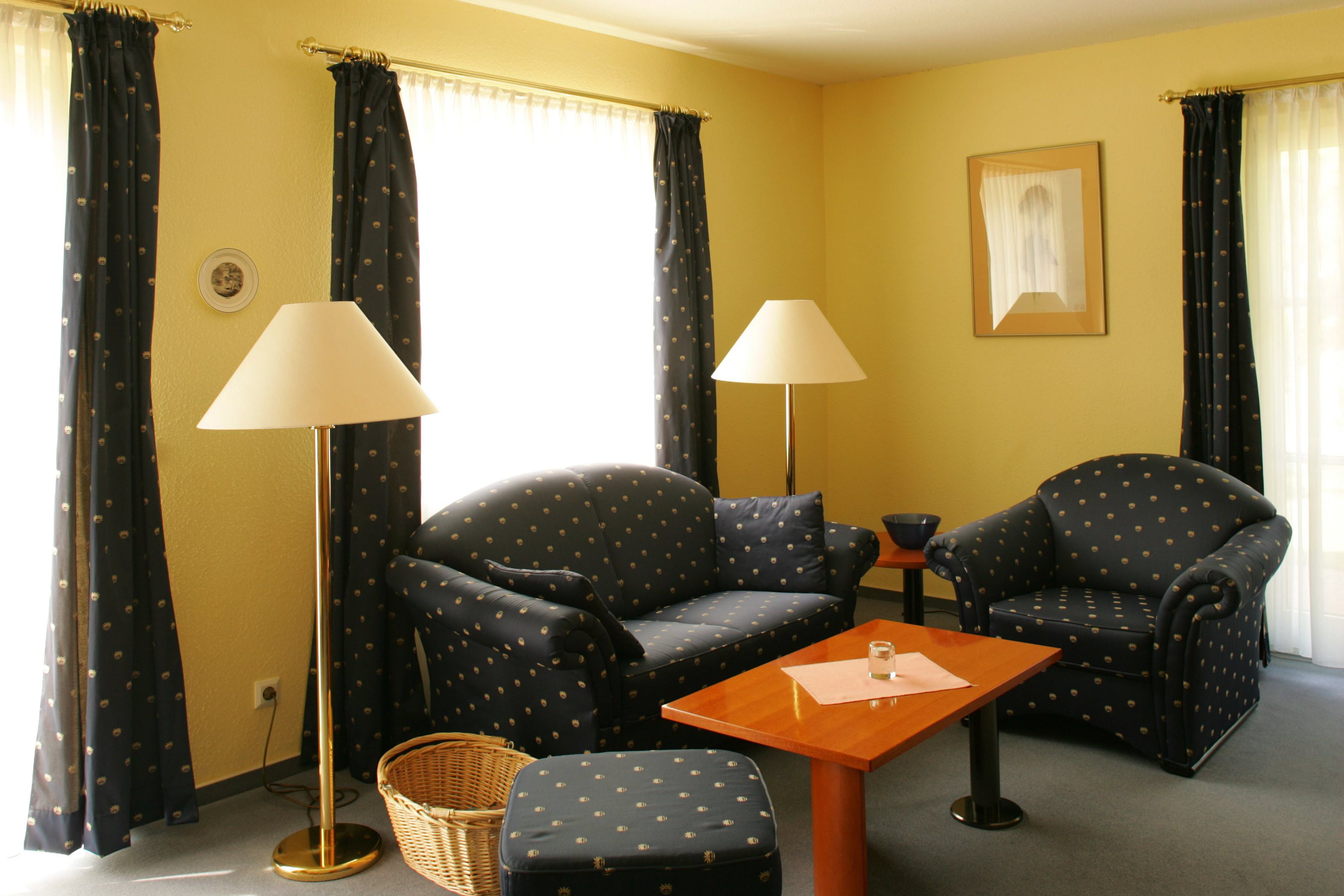 A room with two armchairs, a small table, a floor lamp, and a basket.