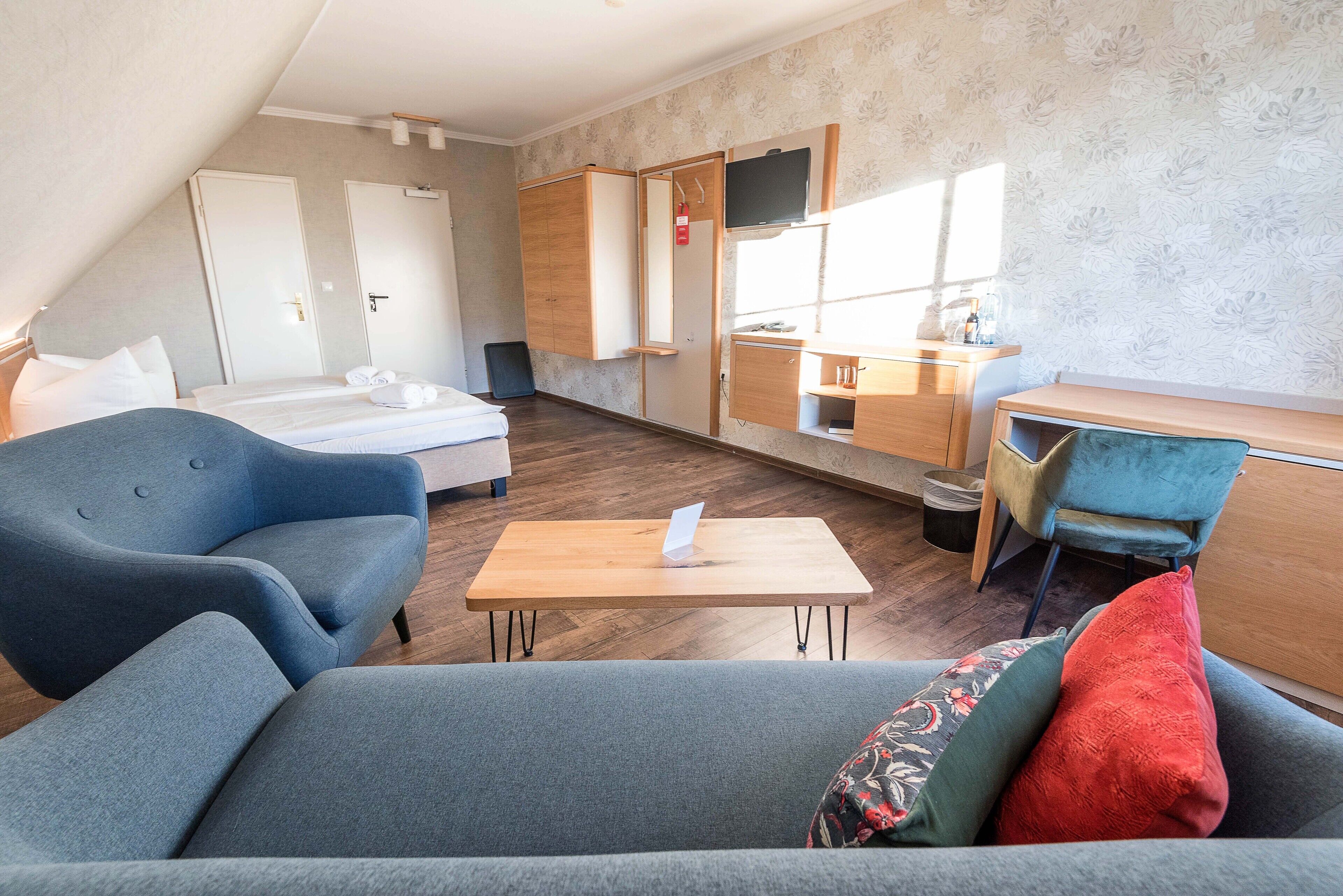 Una habitación de hotel moderna con una cama, un escritorio, una silla y un sofá.