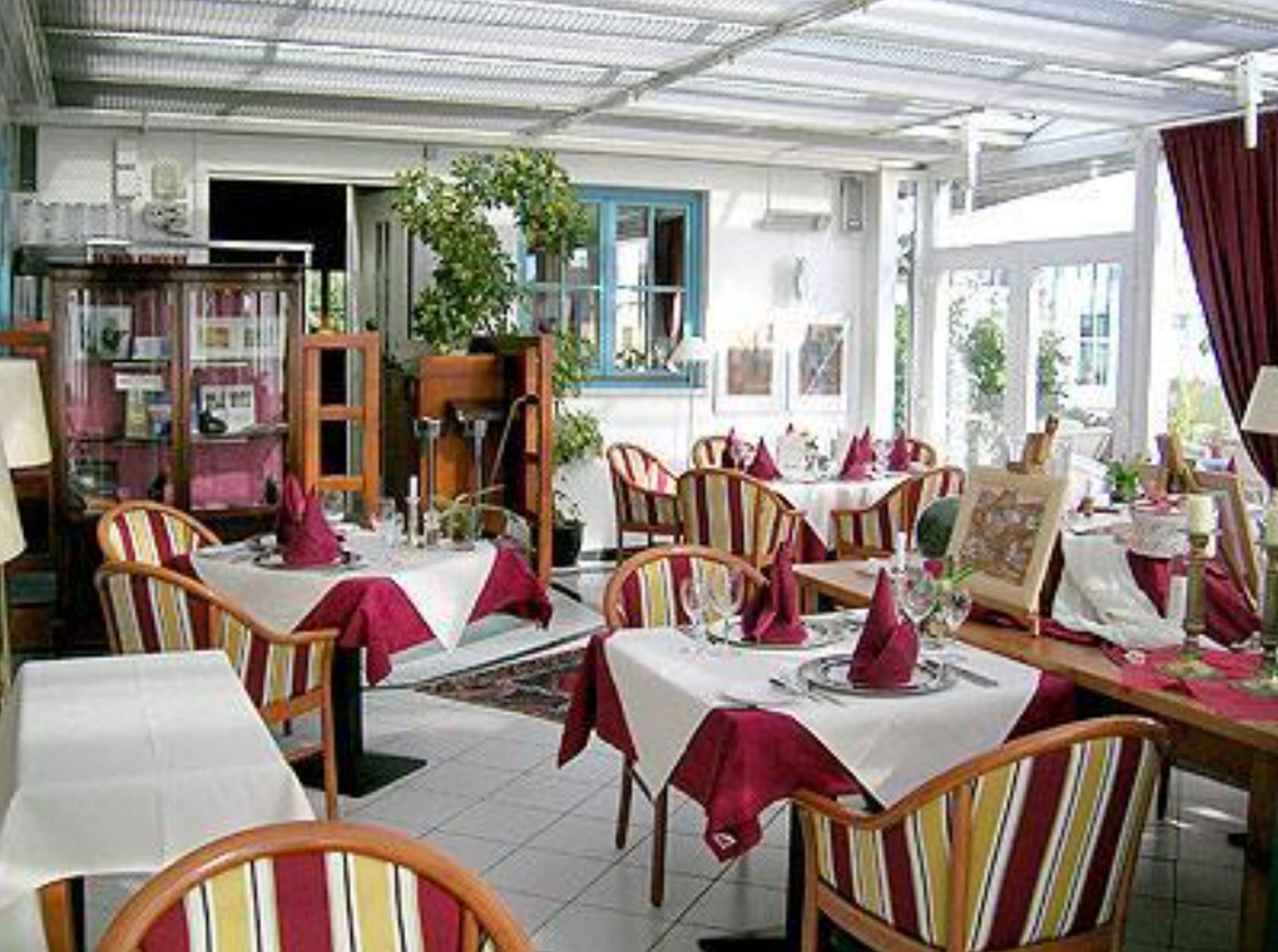 A restaurant with tables set for dining, chairs, and a bookshelf in the background.