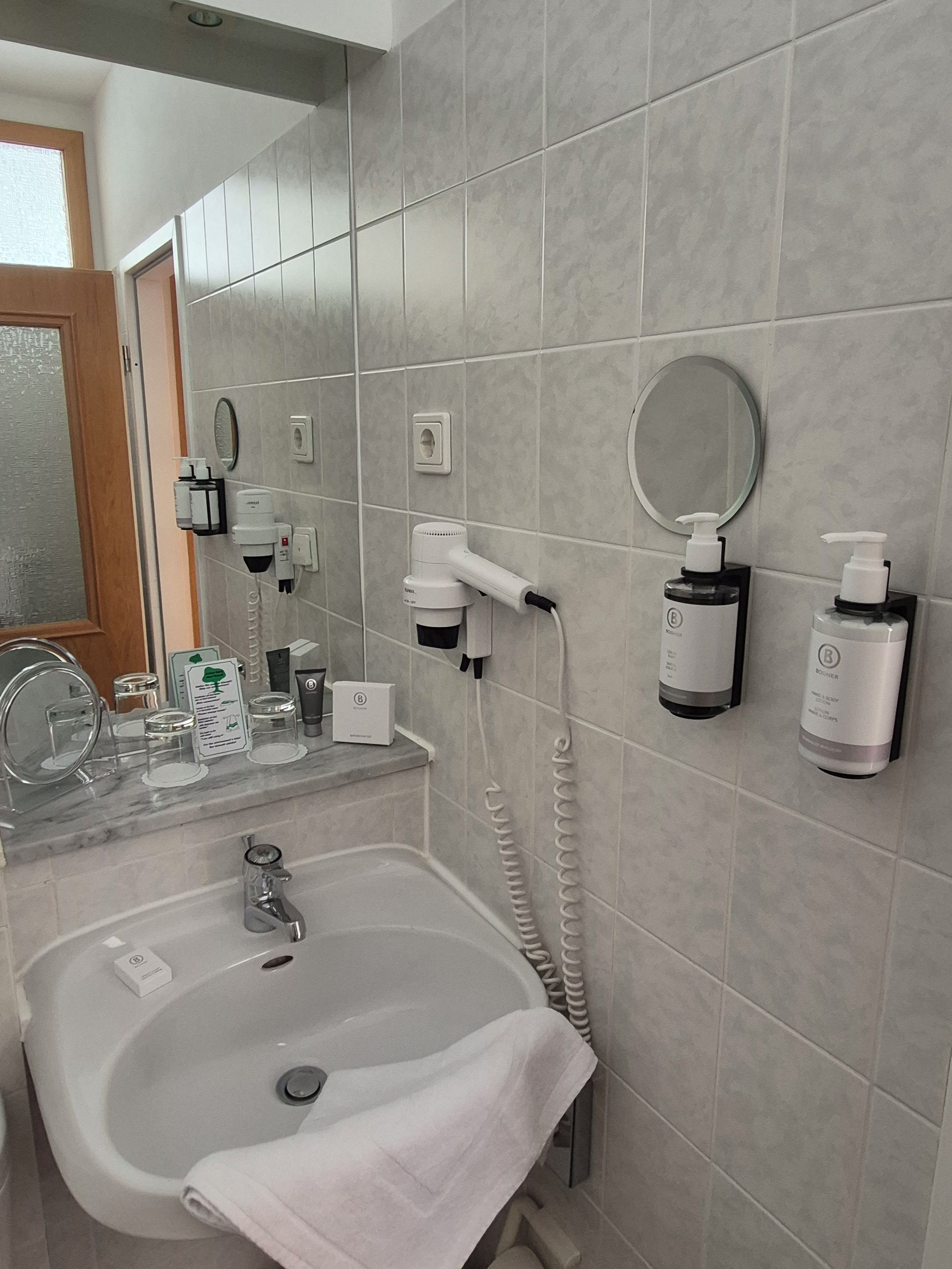 A bathroom with a sink, mirror, towel, and toiletries.