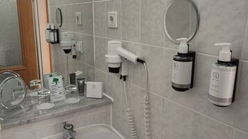 A bathroom with a sink, mirror, towel, and toiletries.