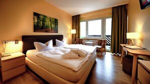 Een hotelkamer met een groot bed, een bureau, een stoel en een raam met gordijnen.