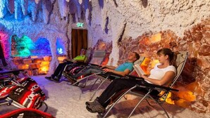 Een geothermal spa met mensen die in stoelen ontspannen, een kleurrijk, grotachtig interieur en een zichtbaar vluchtwegbord.