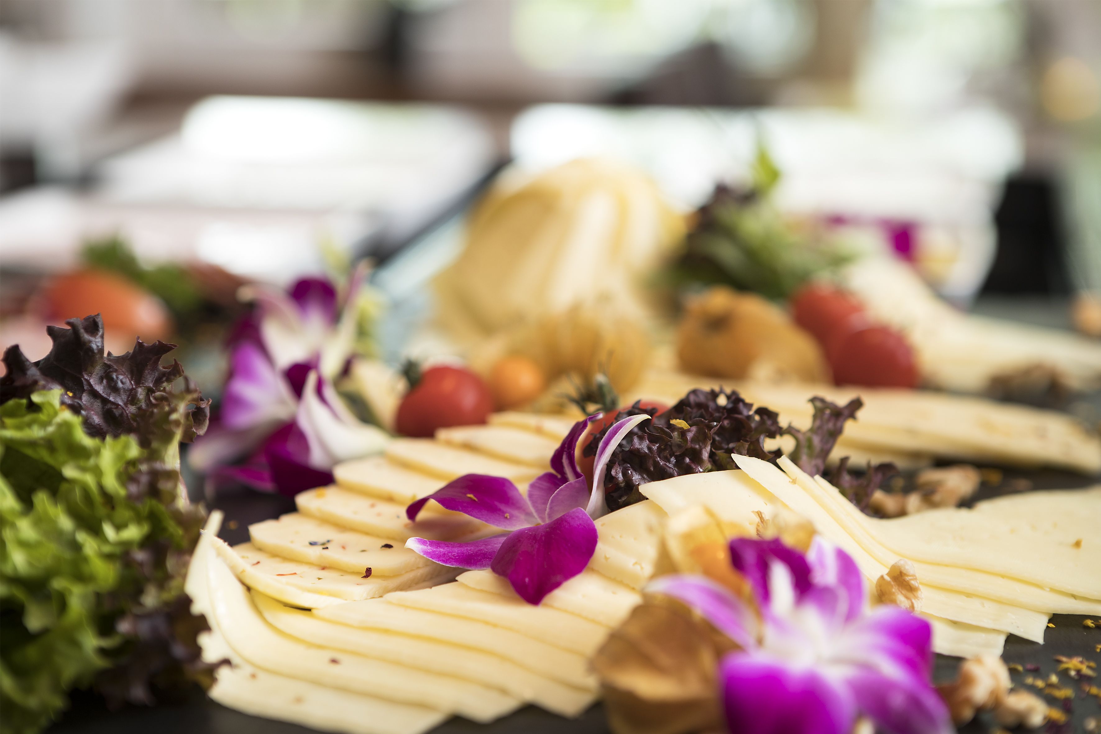A cheese platter with various cheeses, nuts, and flowers.