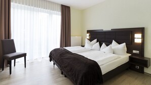 A hotel room with a large bed, a chair, and a nightstand. - Hotel am See (Grevesmuehlen)