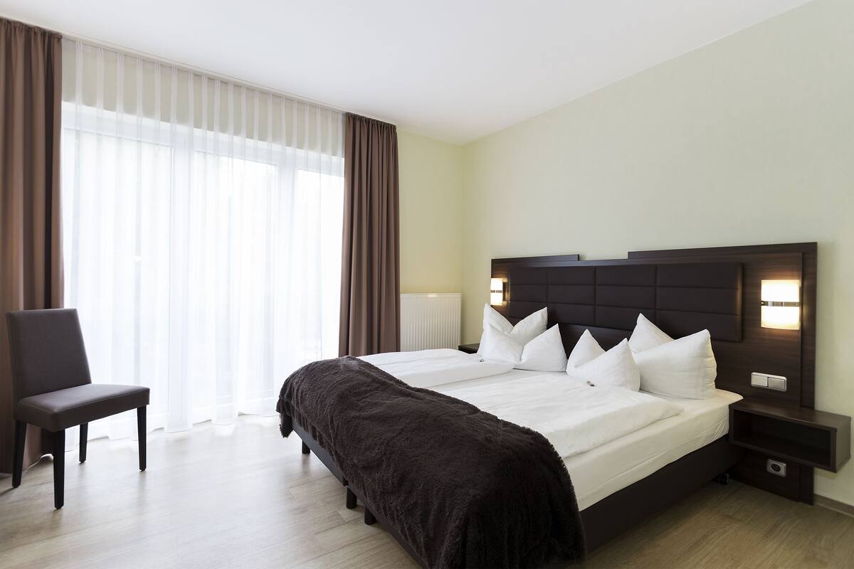 A hotel room with a large bed, a chair, and a nightstand.