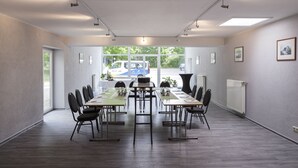 A conference room with a long table, chairs, and a view of the outside. - Hotel am See (Grevesmuehlen)