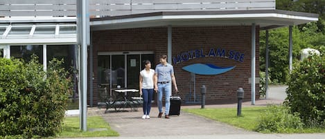 A hotel entrance with a covered patio and a sign reading "HOTEL AM SEE".