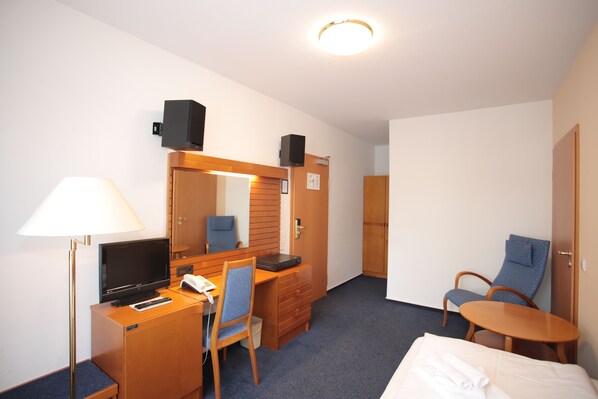 Habitación de hotel con escritorio, silla, cama y una mesita.