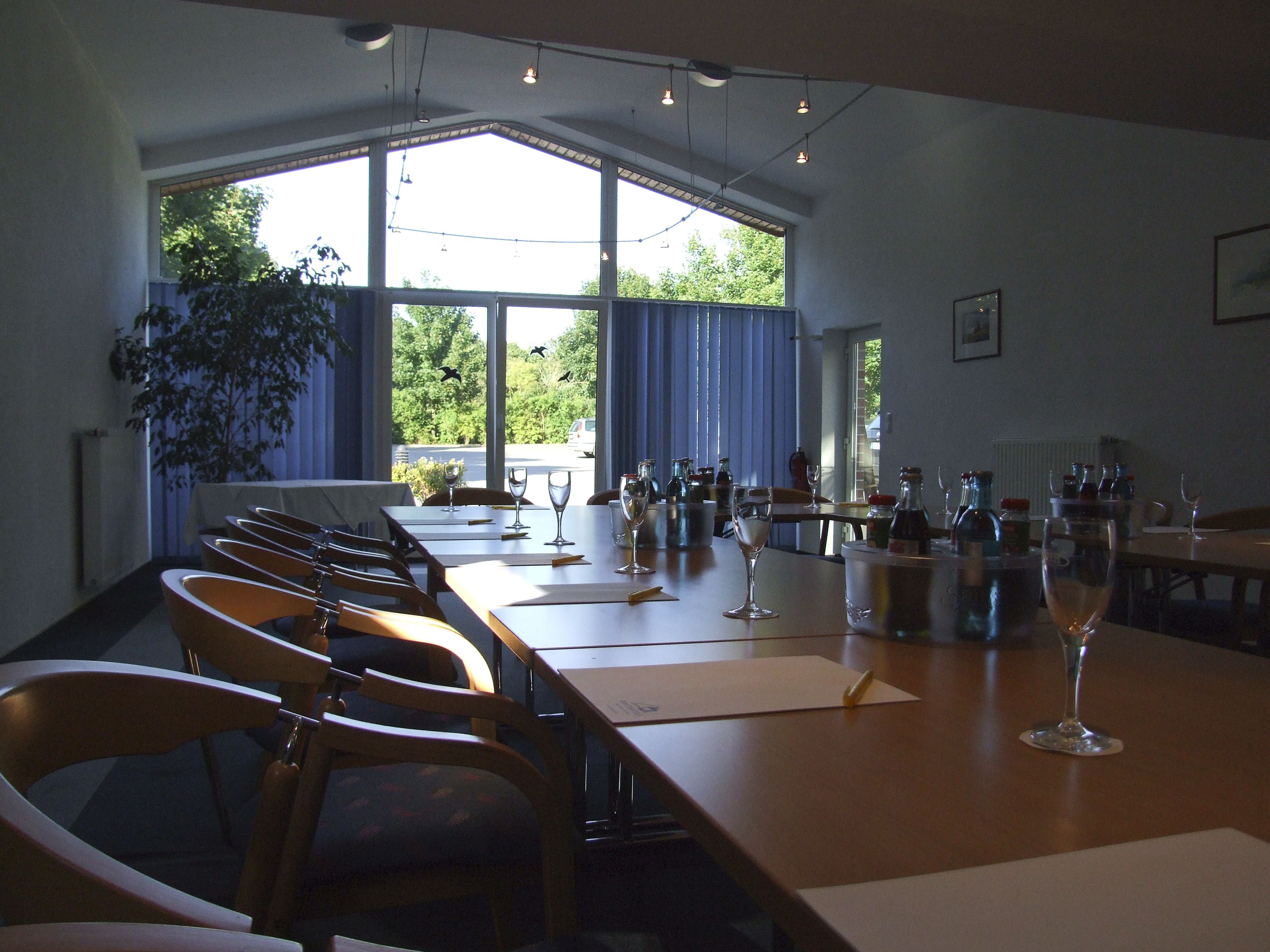 A dining area with a long table, chairs, and wine glasses.
