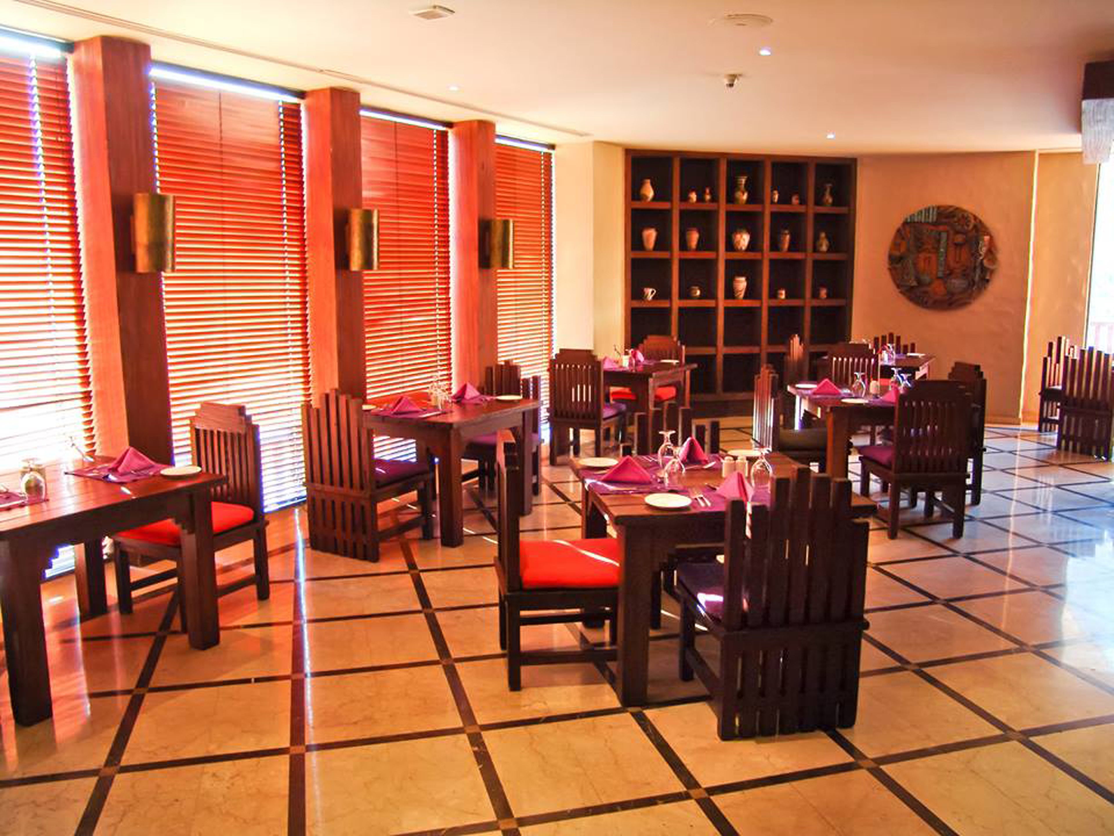 A restaurant with multiple tables and chairs, a tiled floor, and a wall with shelves of decorative items.