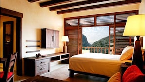 Une chambre à coucher comprenant un lit, un bureau, une chaise, une armoire et une fenêtre donnant sur les montagnes.