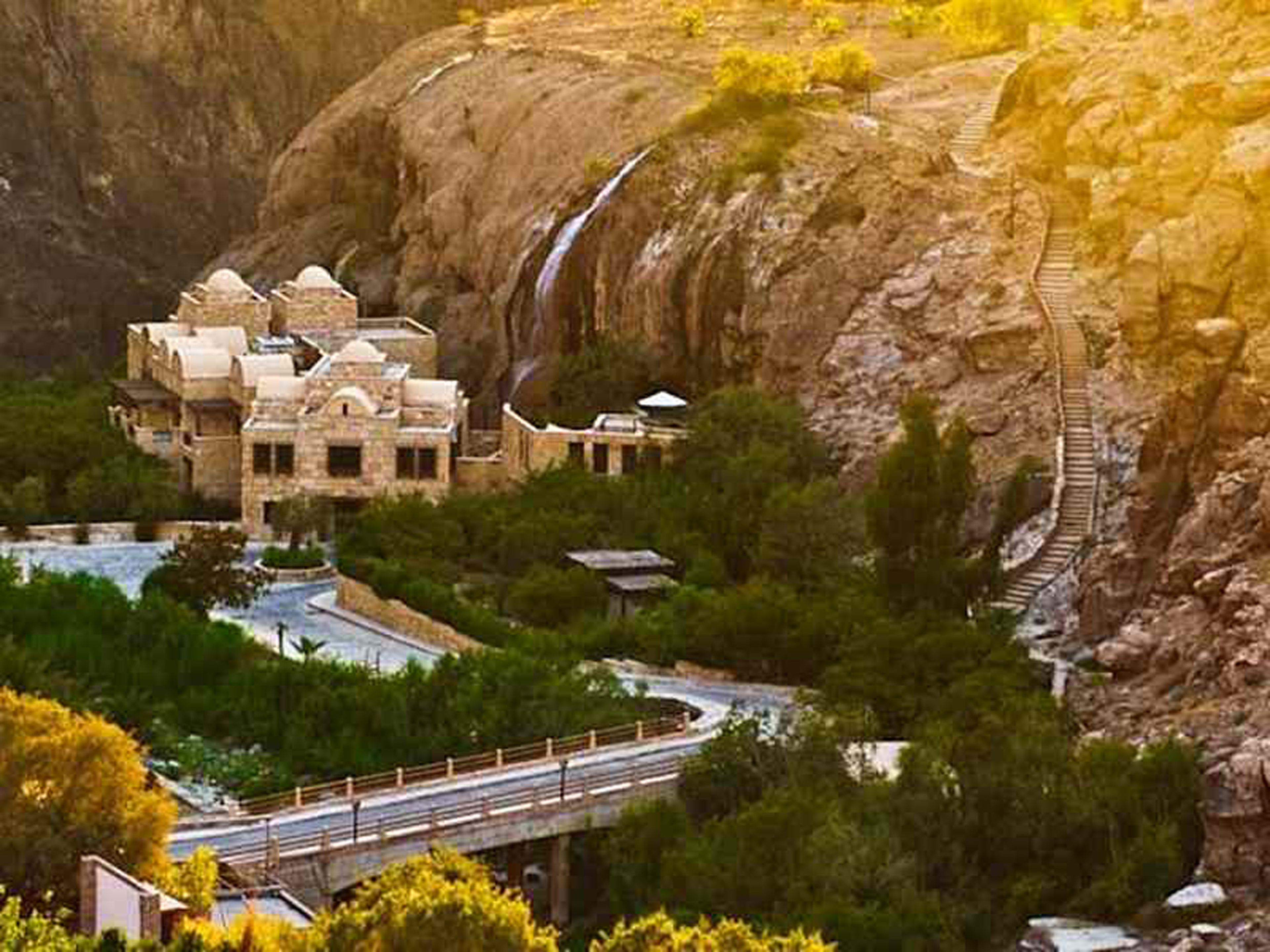 A traditional building with multiple domes, surrounded by lush greenery and a winding road.