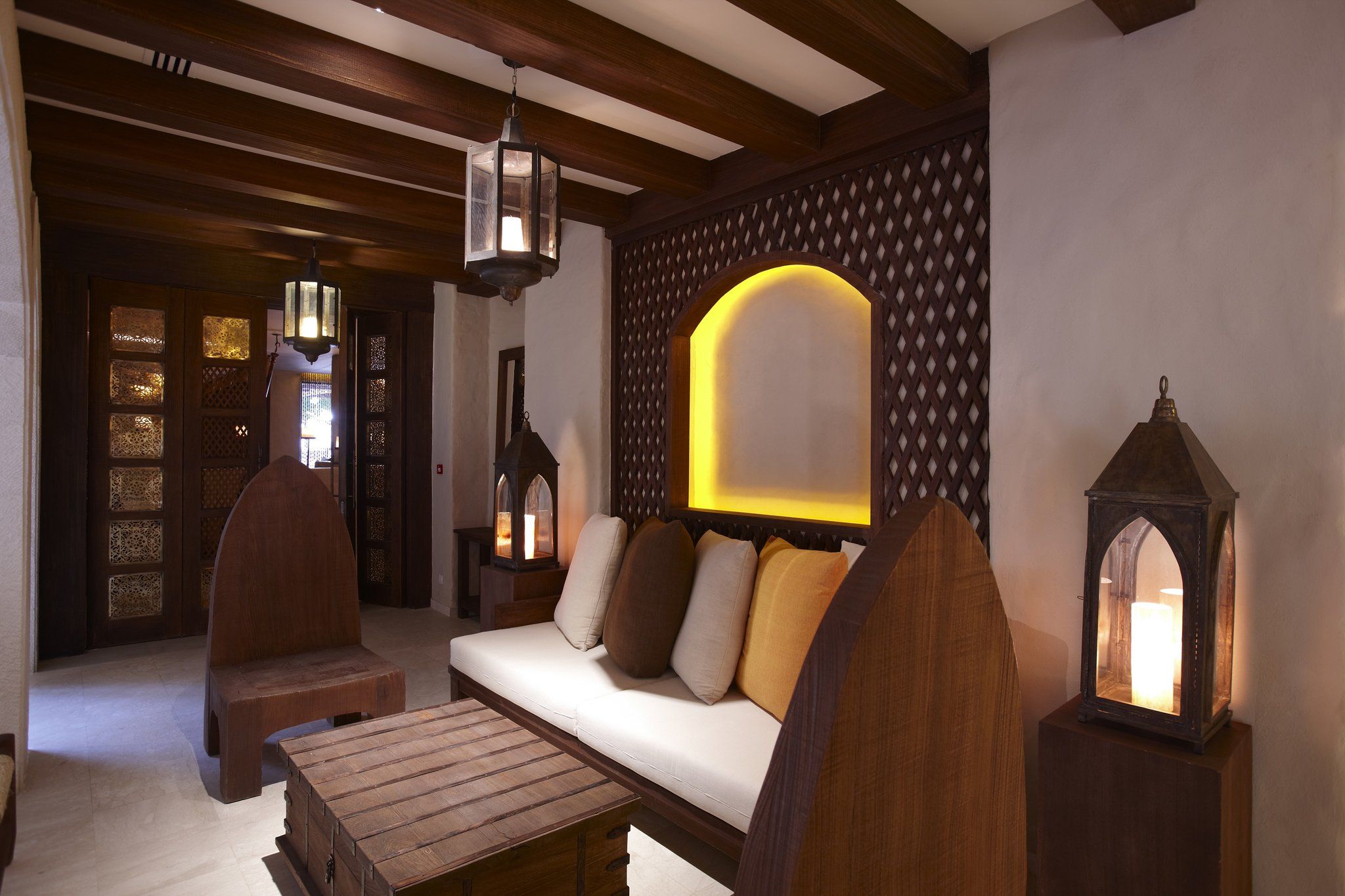 A cozy interior with a wooden bench, a sofa with cushions, and a wall-mounted light fixture.