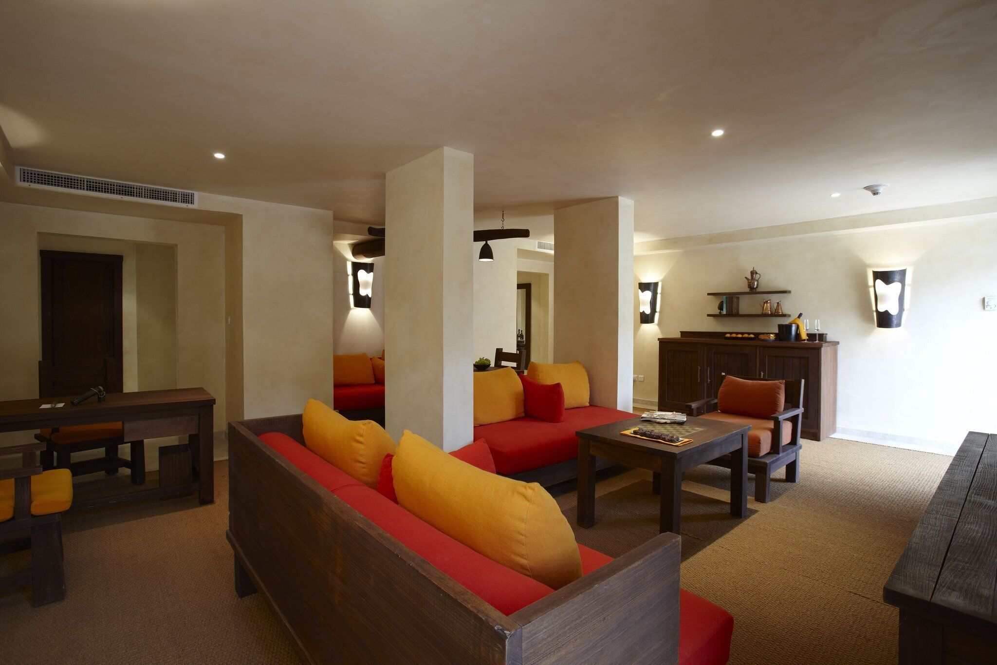 A spacious living area with a wooden bench, a red sofa with yellow cushions, and a coffee table.