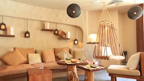 A cozy living room with a sofa, wooden coffee table, and hanging light fixtures.
