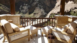 A balcony with wooden furniture and a view of a canyon.